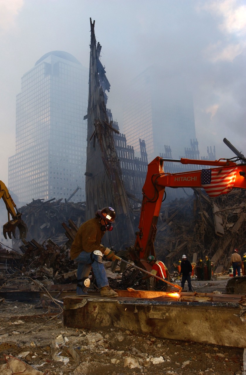 A volunteer steel worker cuts a large part of debris to make it more manageable when it is hauled away from the World Trade Center site, 19 September 2001