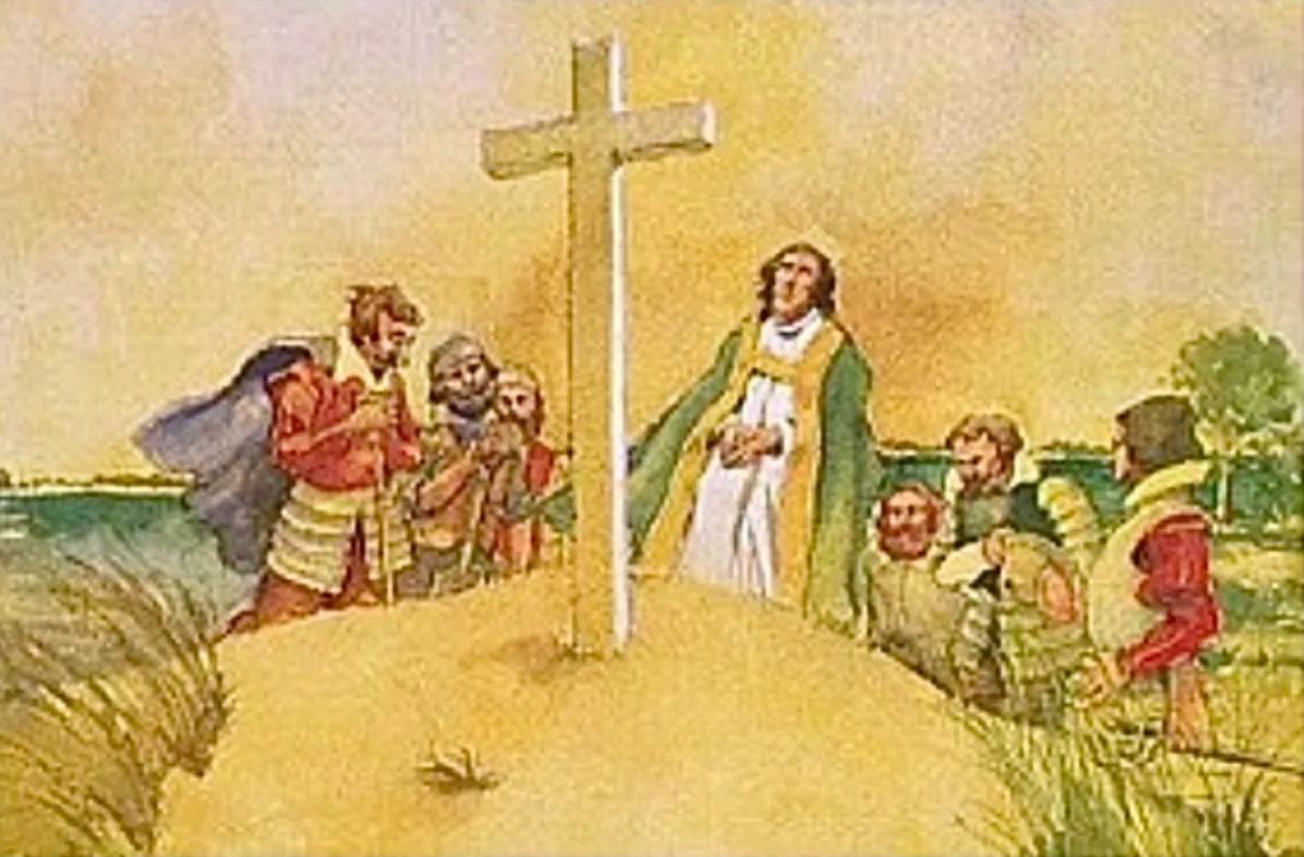people gather around a cross on the beach