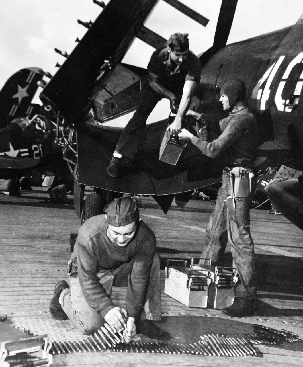 80-G-420997:   Vought F4U Corsair, September 1950.   Ordnance crew arms a F4U “Corsair” with 50 Cal. Ammunition on flight deck of USS Boxer (CV-21) with Task Force 77 in Korea.  Shown:  Ordnanceman Second Class Francis L. Diamond on wing;  and Airmen William J. Ewsuk and Joseph F. Bellina both kneeling.   Photographed on 21 September 1950.  Official U.S. Navy Photograph, now in the collections of the National Archives.  