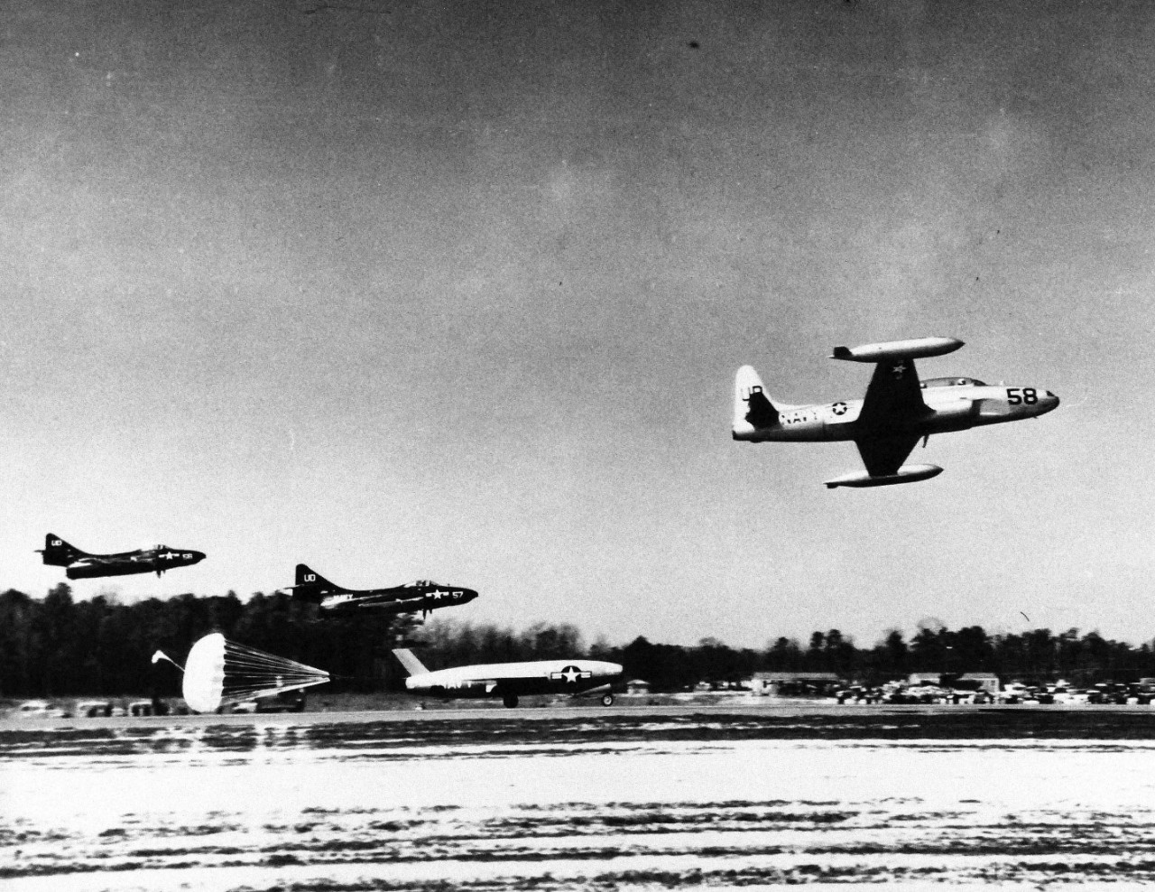 USN 709427:  KDU-1 Regulus, March 1955.   The Navy’s Regulus, KDU-1, radio-controlled jet target drone rolls to a smooth landing with the aid of a parachute brake during a test at the Chincoteague, Virginia, Naval Air Station, March 23, 1955.  The two planes in the background are F9F “Panther” jets.   Official U.S. Navy photograph, now in the collections of the National Archives.  