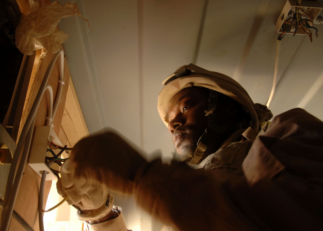 061130-N-6889J-076:   Construction Electrician Second Class Jumoke Freitas, November 2006.  Construction Electrician 2nd Class Jumoke Freitas of Naval Mobile Construction Battalion 74 (NMCB 74) re-wires a junction box at an Iraqi Police Station in Ramadi on Nov 30.   Seabees from NMCB74 currently deployed to Ramadi, assist the Iraqi Police, Soldiers and Marines on the front lines by upgrading current living conditions and helping establish new combat out post throughout the area.  Photographed on November 30, 2006 by Mass Communications Specialist 2nd Class Gregory N. Juday  Official U.S. Navy Photograph.   