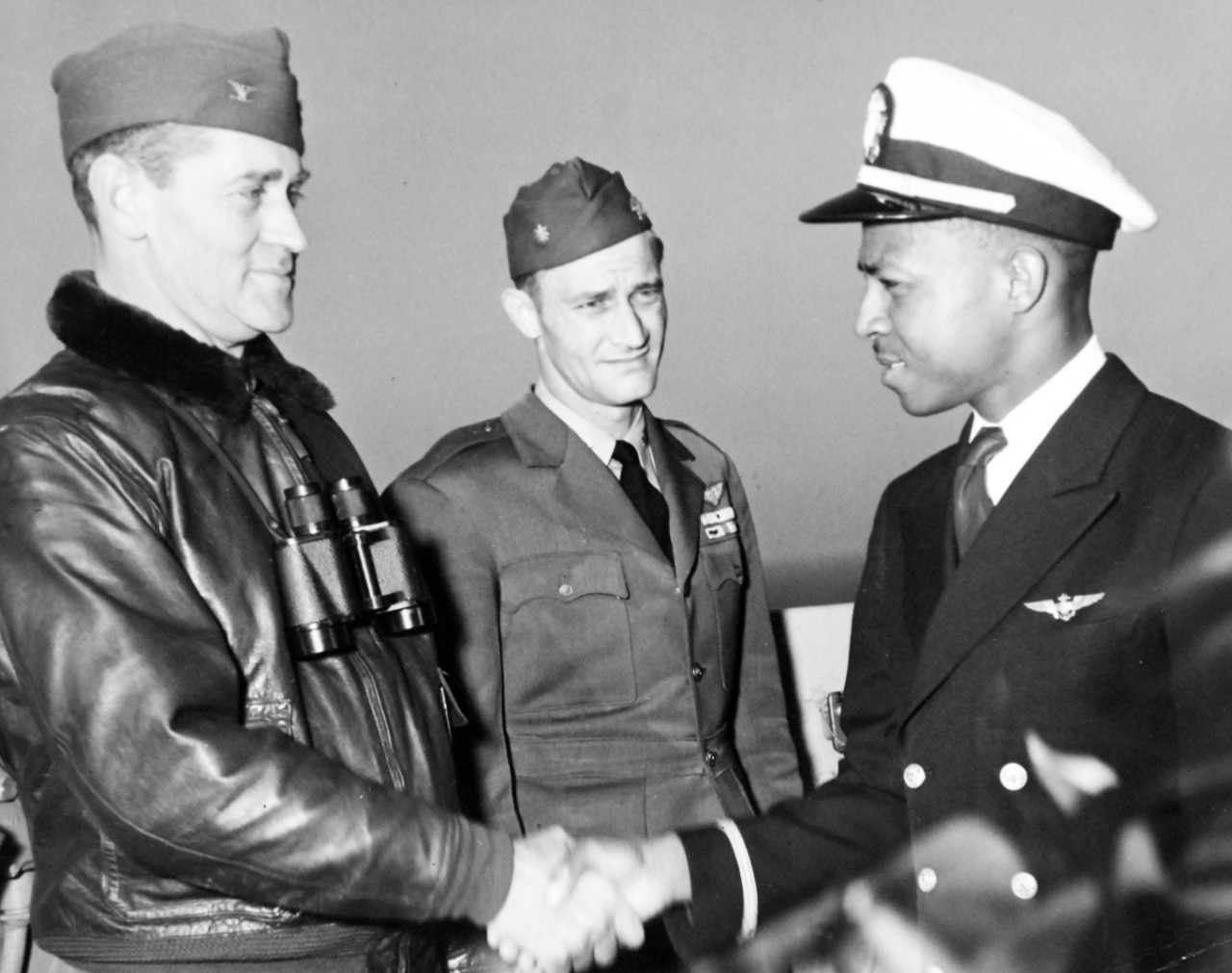 80-G-404869:   Ensign Jesse L. Brown, USN, April 1949.  First African American Aviator Ensign Jesse L. Brown shaking hands with Captain W.L. Erdman, Commanding Officer of USS Leyte (CV-32).  Shown, L to R: Captain W.L. Erdman, Lieutenant Commander E.D. Williams, CO of VF-32, and Ensign Brown.  Official U.S. Navy Photograph, now in the collections of the National Archives.  