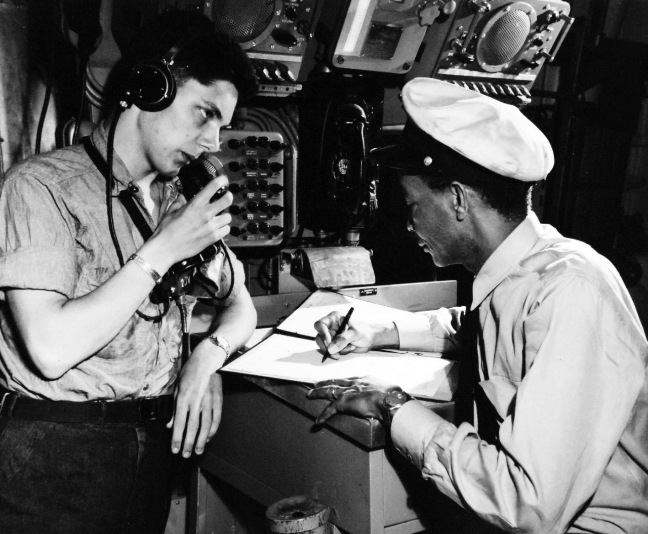 80-G-413546:   USS Coral Sea (CVA 43), May 5, 1949.    CMM Leslie Ponder makes entries in main engine room while FA J. Toles wears telephone headset and relays reports to the Chief from various engineering spaces of the ship.  Official U.S. Navy Photograph, now in the collections of the National Archives.  