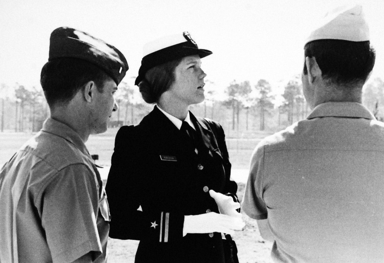 428-GX-USN-1156075:  Lieutenant Junior Grade Shelly Robinson,  (center), July 1973.   Robinson chats with two male officers during a break between classes at the Air Traffic Control Officer School, Naval Air Station, Glynco, Georgia.    Miss Robinson is the first woman of the Navy to attend the school.   Photographed by PH1 John P. Francavillo, received July 1973.  U.S. Navy Photograph, now in the collections of the National Archives.  