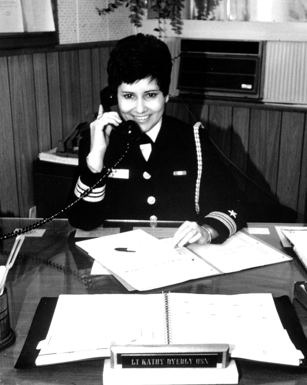 K-312754:   Lieutenant Kathleen M. Byerly, February 1976.    Byerly, Flag Secretary and Aide to Rear Admiral Allen E. Hill, Commander, Training Command, Pacific, talks on the telephone in her office at the Fleet Training Center.  She was chosen by “Time” Magazine as one of their twelve “Women of the Year” for 1975.    Photographed by Lieutenant Byerly, February 12, 1976.  Official U.S. Navy Photograph, now in the collections of the National Archives.  Black and white only. 
