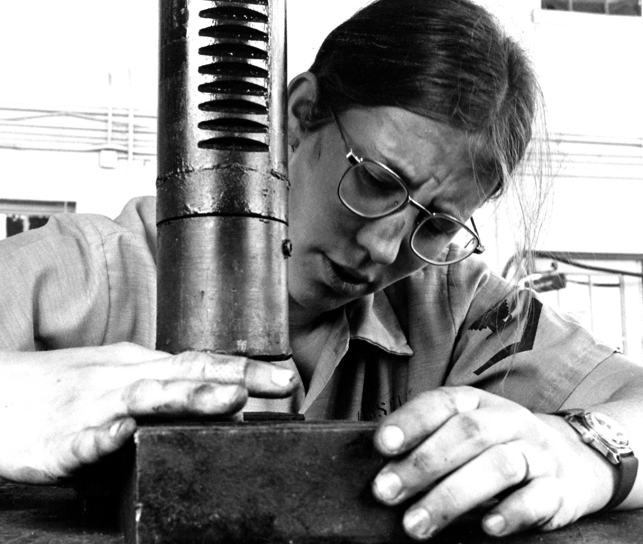 USN 1165723:   Engineman Third Class Cathy Russell, June 1975.   Russell concentrates on the task at hand as she works to repair equipment at the boat house at U.S. Naval Air Station, North Island, San Diego, California.   Photographed by PHAN Jo Cooper.   Official U.S. Navy photograph, now in the collections of the National Archives.  