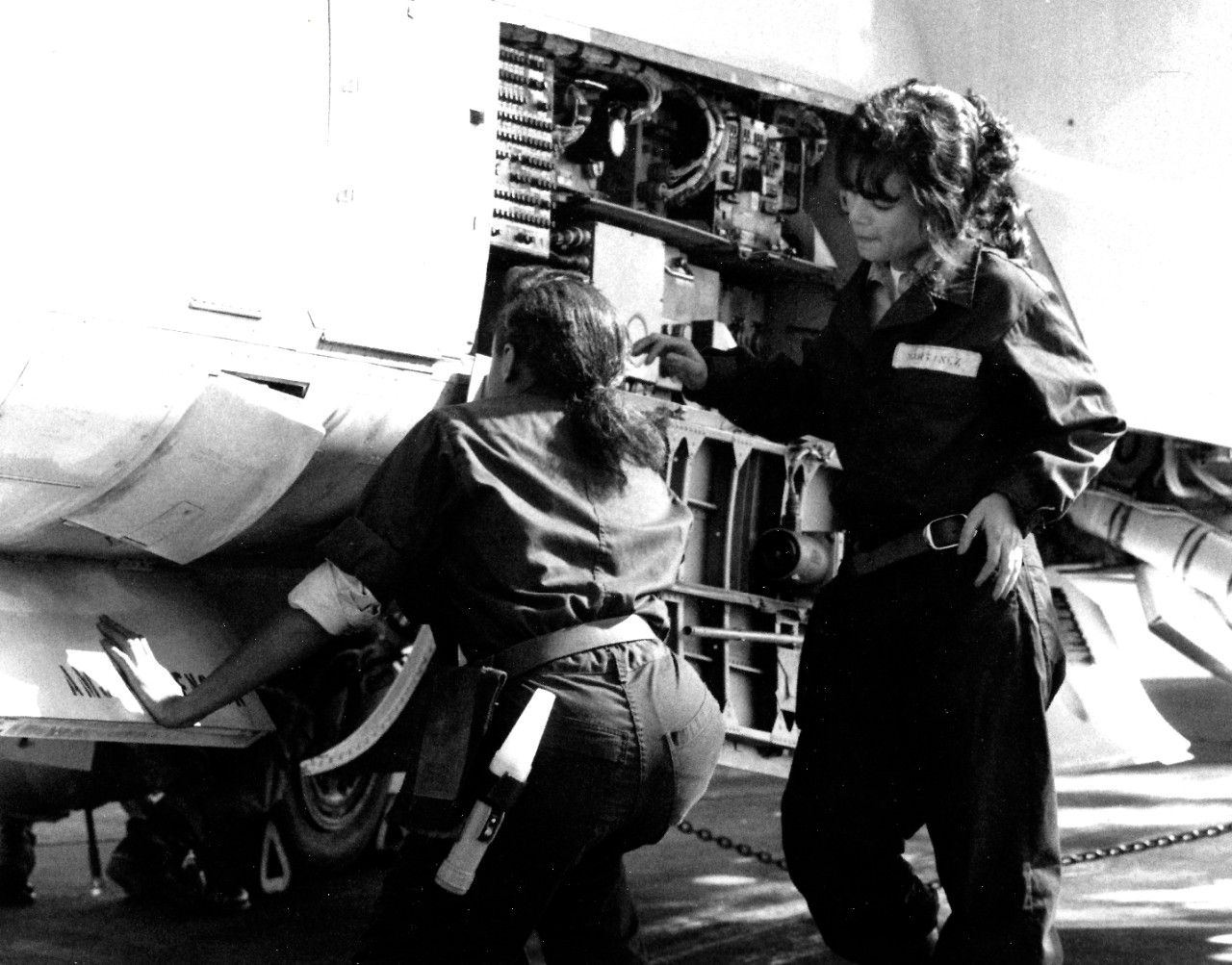 330-CFD-DN-SN-89-01677:   Female Airmen, November 1988.    Airman Ora Howard, Plane Captain, (left), and Airman Grisselle Martinez,  perform a routine maintenance on an A-7 Corsair II aircraft.   Photograph by JO3 Cyndi Reilly and received November 22, 1988.    Official U.S. Navy Photograph, now in the collections of the National Archives.