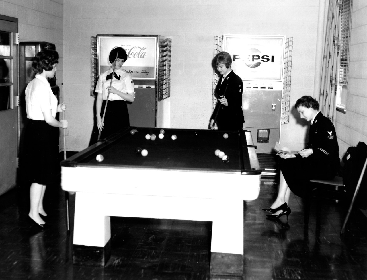 KN-8694 (Color):   Naval Station, Norfolk, Virginia, May 1, 1963.   Game room in WAVES Barracks, B-30.   Left to right:  DKSN Sue Frederick, SN Rosemary Costello, DN Sharon Slauson, and YN2 Mary Ross.  Photographed by PH3 Pullen.  Official U.S. Navy Photograph, now in the collections of the National Archives.   Note, image is black and white only at the museum.   