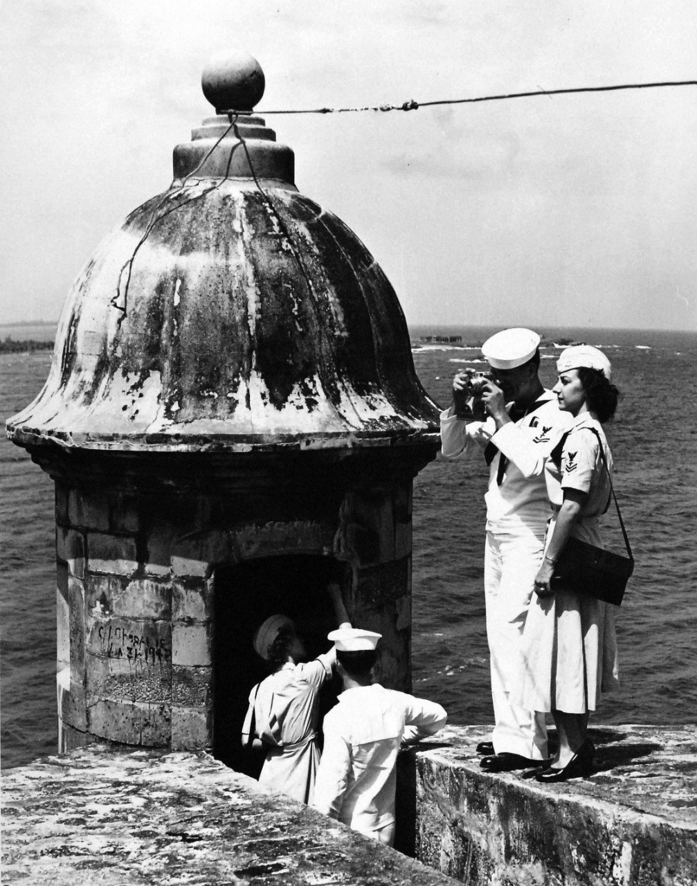 USN 709020:   WAVES and friends on Liberty, October 1953.   One of El Morro’s ancient lookout towers is inspected by HM3 Marie Myers; YN2 Harold Baker , while HM2 Joseph La Freniere and HM2 Eileen Paluzzi take pictures of the fort.   Photograph released October 26, 1953.   Master Caption:   Navy Accepts Women Volunteers for Duty on the High Seas.   For the first time in history, the U.S. Navy has accepted volunteers for duty on the high seas from women in the enlisted WAVES.  Those eligible were WAVES of the Hospital Corps to fill sixty-three billets on ships of the Military Sea Transportation Service.   Official U.S. Navy photograph, now in the collections of the National Archives.   