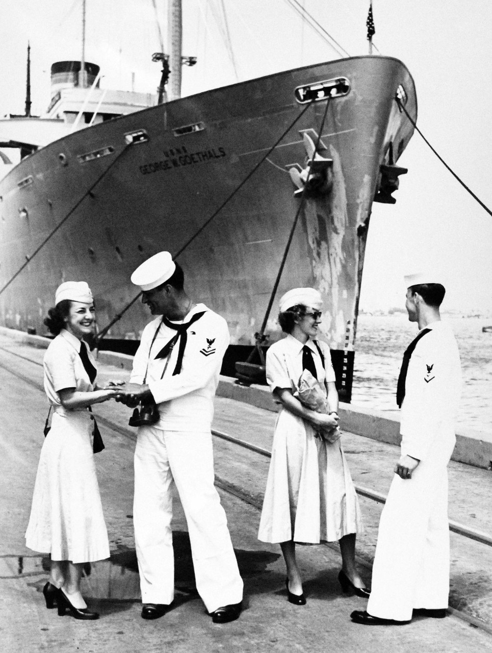 USN 709026:   Liberty Expires for WAVES, October 1953.   A few minutes before the girls’ liberty was up, their sailor escorts returned the WAVES to their ship, USNS George M. Goethals (T-AP-182).    The two young ladies thanked their escorts for a pleasant time.  In a reversal of usual Navy routine, the WAVES reported onboard their ship  (in background) – this time, the boys were “left behind.”   Left to right:  Paluzzi, LaFreniere, Myers and Baker.   Photograph released October 26, 1953.   Master Caption:   Navy Accepts Women Volunteers for Duty on the High Seas.   For the first time in history, the U.S. Navy has accepted volunteers for duty on the high seas from women in the enlisted WAVES.  Those eligible were WAVES of the Hospital Corps to fill sixty-three billets on ships of the Military Sea Transportation Service.   Official U.S. Navy photograph, now in the collections of the National Archives.   