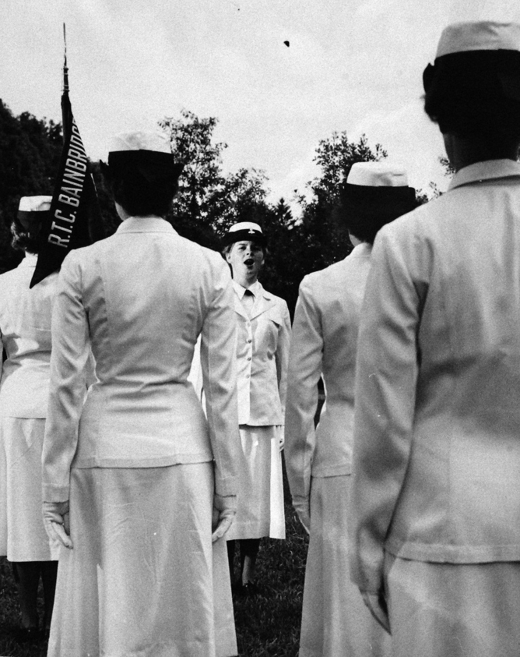 USN 709488:    Seaman Apprentice Barbara Boyd, July 1955.  Boyd is an example of the young women presently undergoing WAVE Recruit Training at the Naval Training Center, Bainbridge, Maryland.  She is shown announcing orders to the other recruits.   Master Caption:  WAVES Observe 13th Anniversary:   Preparatory to their Thirteenth Anniversary, July 30, WAVE Recruits at the Naval Training Center, Bainbridge, Maryland, pass in review.  These young women will take their places with sailors in important technical and clerical duty assignments both at home and abroad.  At that time, there were approximately 7,000 WAVES on active duty in the U.S. Navy.   Photograph released July 25, 1955.  Official U.S. Navy photograph, now in the collections of the National Archives.   