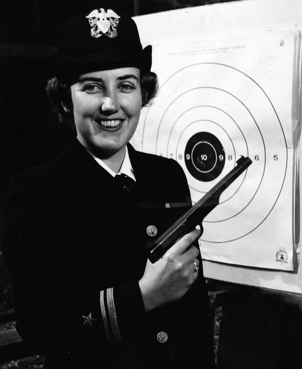 USN 709565:   U.S. Navy WAVE Lieutenant (Junior Grade) Nancy Jane Ellifrit, March 1956.   Ellifrit displays her shooting ability at the Park Police Range in Washington before departing for the National Mid-Winter Pistol Meet at Tampa, Florida that March.    Lieutenant Ellifrit was the only WAVE participating in the meet.  She has been shooting since she joined the U.S. Navy in August 1952 and is qualified in 22, 38, and 45-caliber pistols.   She has attended the Nationals for the past three  years as a member of a Bureau of Ordnance Team composed of these WAVES and a the wife of a U.S. Navy Commander.   Ellifrit won the Virginia State Women’s Championship the last year.   Photograph released March 7, 1956.   Official U.S. Navy photograph, now in the collections of the National Archives.   