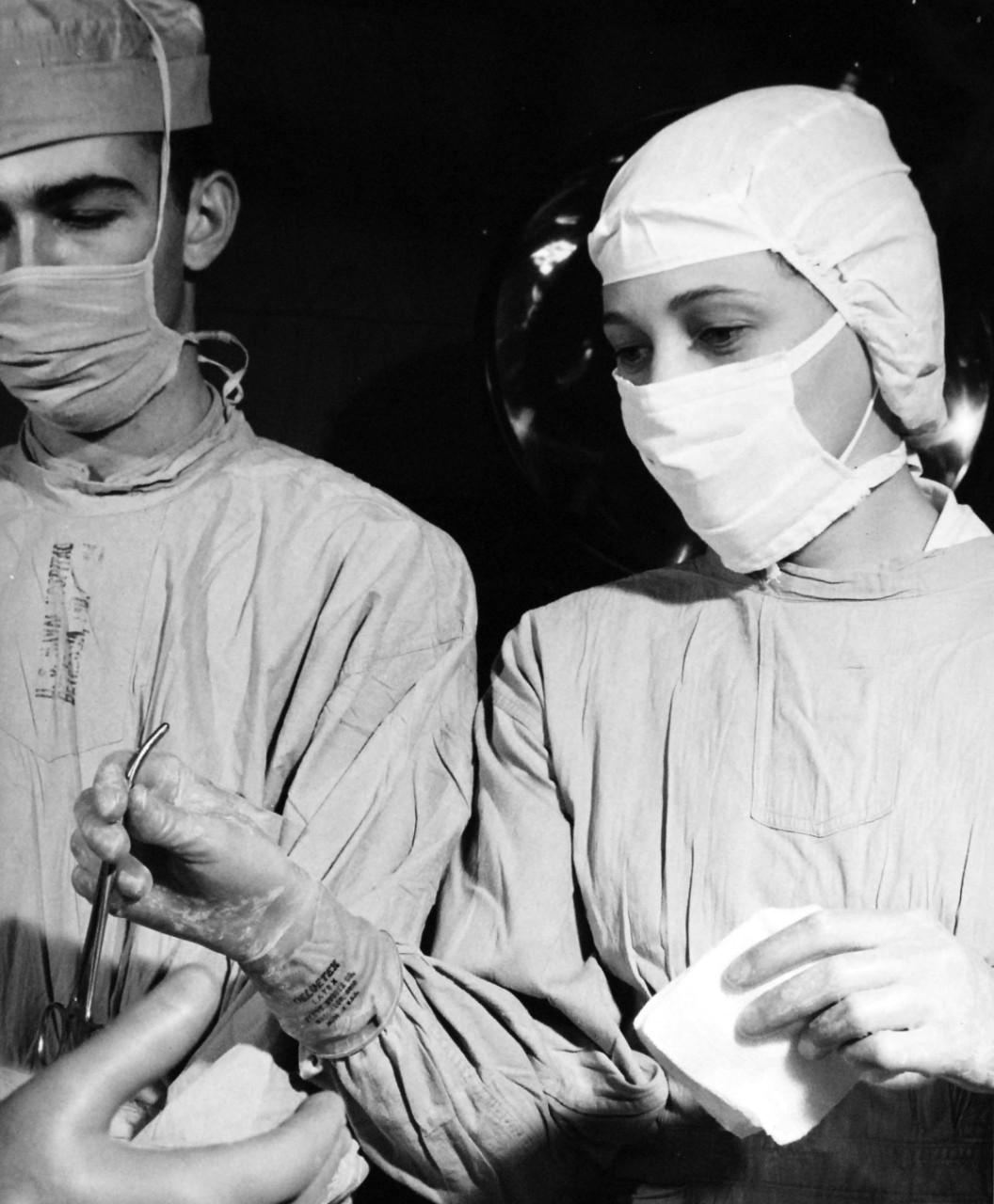 USN 709744:  U.S. Navy Nurse, Ensign Shirley W. Muse, NC, USNR, January 1957.   Muse passes instruments to a surgeon in the course of an operation at the U.S. Naval Hospital, Bethesda, Maryland.   Photograph released January 4, 1957.   Official U.S. Navy photograph, now in the collections of the National Archives.   