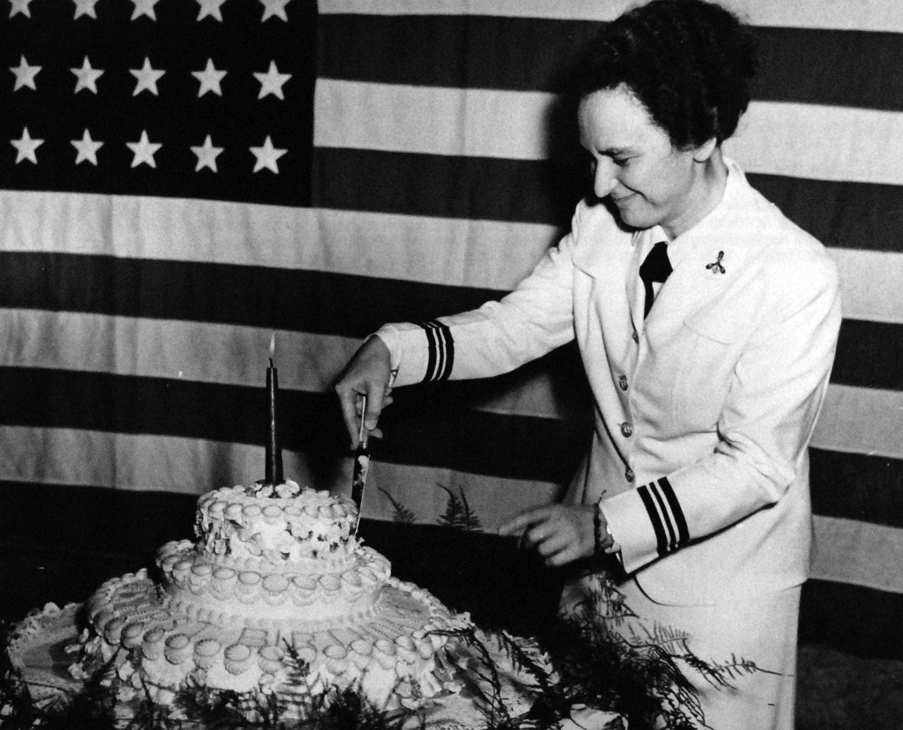 80-G-42486:   Celebration of the WAVES’ first anniversary, July 1943.   Lieutenant Commander Mildred H. McAfee, Director of the Women’s Reserve of the Navy, cuts the cake at a dance held at the Mayflower Hotel, Washington, D.C.,  July 30, 1943.  Official U.S. Navy photograph, now in the collections of the National Archives.  