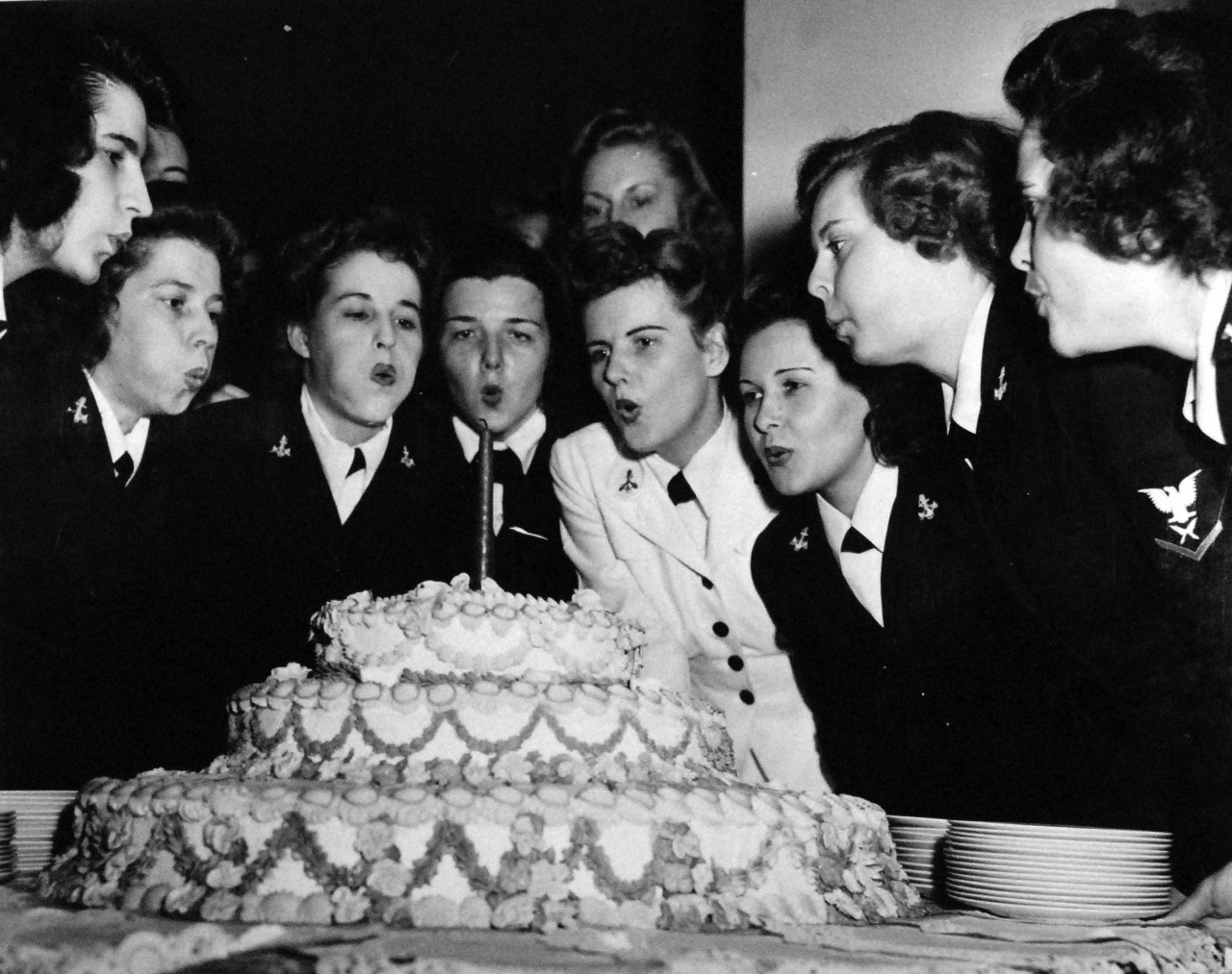 80-G-42493:  Celebration of the WAVES first anniversary, July 1943.  The object of the big blow is that single candle illuminating the birthday cake at a party held at Quarters A, Washington, D.C.   Official U.S. Navy photograph, now in the collections of the National Archives.  