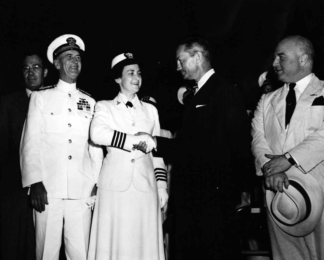 80-G-46253:  WAVES in Washington, D.C. July 1944.   WAVES hold rally at Washington Monument Grounds to celebrate the second anniversary of the establishment of the Women’s Reserve of the U.S. Navy.  Secretary of the Navy James Forrestal congratulates the Women’s Reserve on two years of service as he shakes hands with Captain Mildred H. McAfee, USNR; Assistant Secretary of the Navy for Air Artemus L. Gates, Admiral Ernest J. King, USN, and Representative Melvan J. Mass, smiling look on.   Released July 31, 1944.  Official U.S. Navy Photograph, now in the collections of the National Archives.  