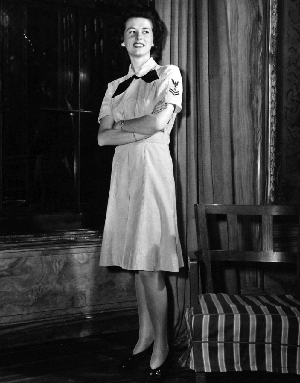 80-G-46606:  Working Uniform, June 1944.  Correct uniforms worn by enlisted personnel of the Women’s Reserve, U.S. Naval Reserve, are modeled by Specialist (R)2c Jeanne Henry, attached to the Office of Naval Officer Procurement, in New York City.  This gray and white cotton seersucker dress is worn indoors without the matching jacket.   Released June 22, 1944.  U.S. Navy Photograph, now in the collections of the National Archives.  