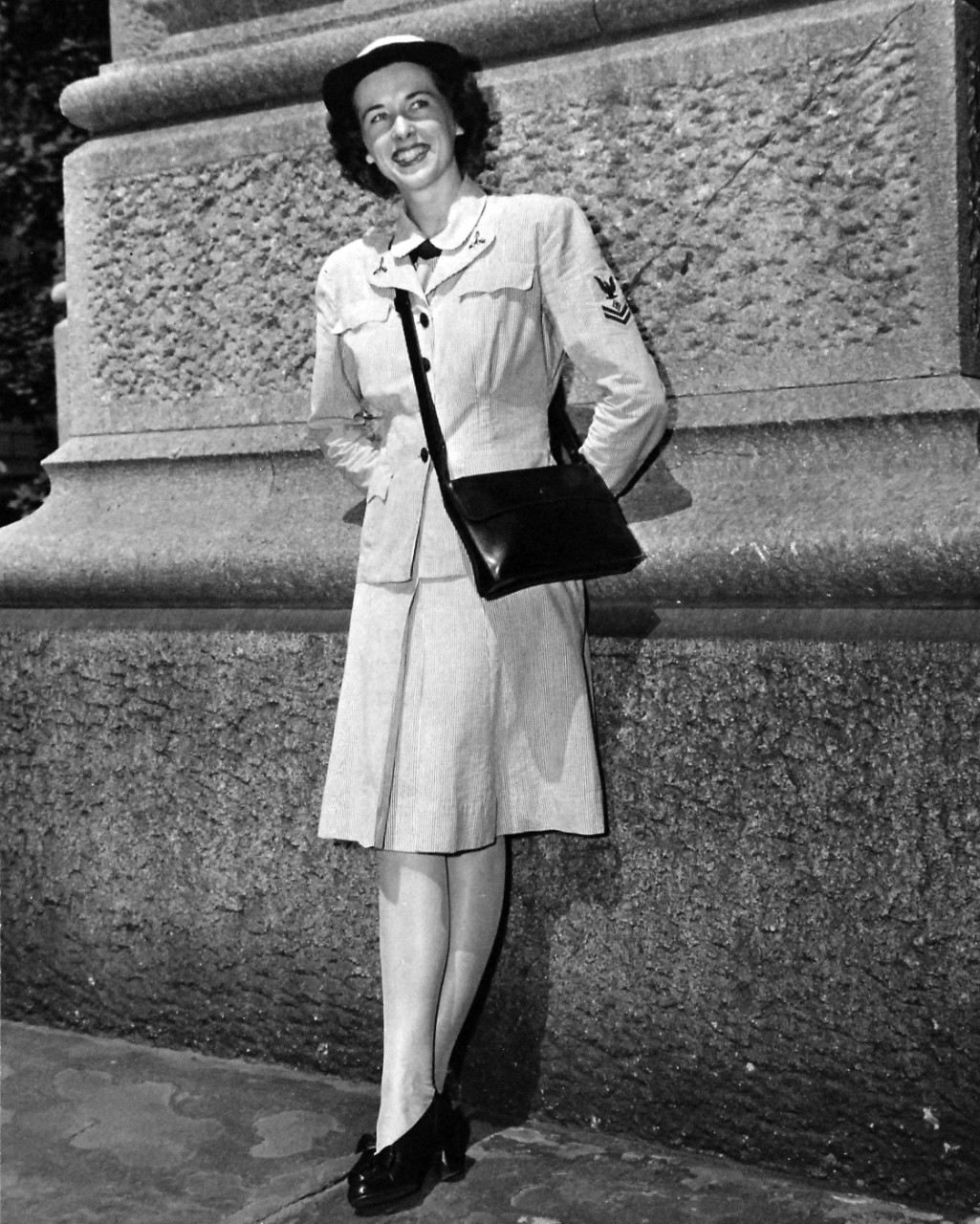 80-G-46608:  Working Uniform (front), June 1944.  Correct uniforms worn by enlisted personnel of the Women’s Reserve, U.S. Naval Reserve, are modeled by Specialist (R)2c Jeanne Henry, attached to the Office of Naval Officer Procurement, in New York City.  This uniform consists of a gray and white cotton seersucker dress with matching jacket and hat cover.  The black gloves are optional.   Released June 22, 1944.  U.S. Navy Photograph, now in the collections of the National Archives.  