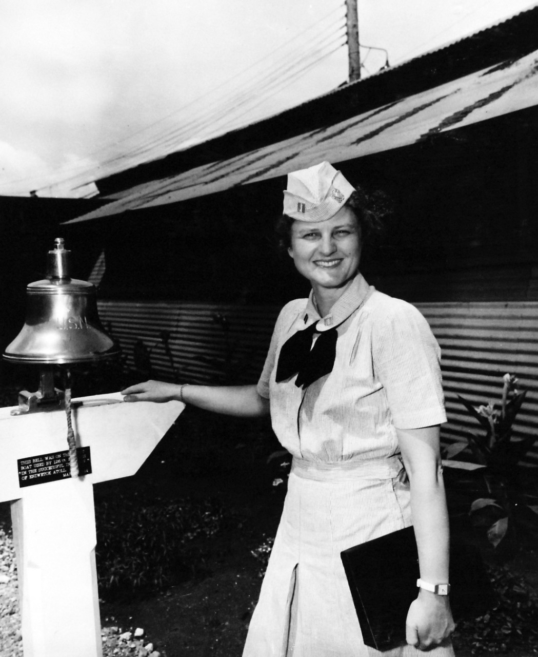 80-G-49770:  Working Uniform, July 1945.   Lieutenant Francis Rich beside ship’s bell presented to WAVES by a Seabee Battalion, Pearl Harbor, Territory of Hawaii.  Released July 2, 1945.   Official U.S. Navy photograph, now in the collections of the National Archives.  