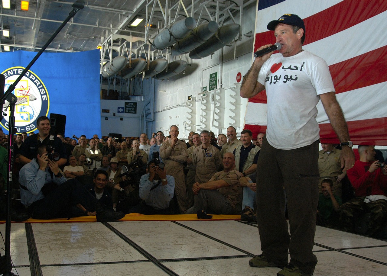 031219-N-9742R-001:  USS Enterprise (CVN-65), 2003.   Actor/comedian Robin Williams entertains the Enterprise crew during a holiday special on board   hosted by the United Service Organization (USO) in Hangar Bay One, also featuring the Chairman of the Joint Chiefs of Staff, General Richard Myers, NASCAR driver Mike Wallace, and WWE wrestler Kurt Angle, Arabian Gulf, December 19, 2003. Official US Navy photo by Photographer's Mate Airman Milosz Reterski. Image released by LT K.R. Stephens, PAO CVN-65.   Official U.S. Navy Photograph.         