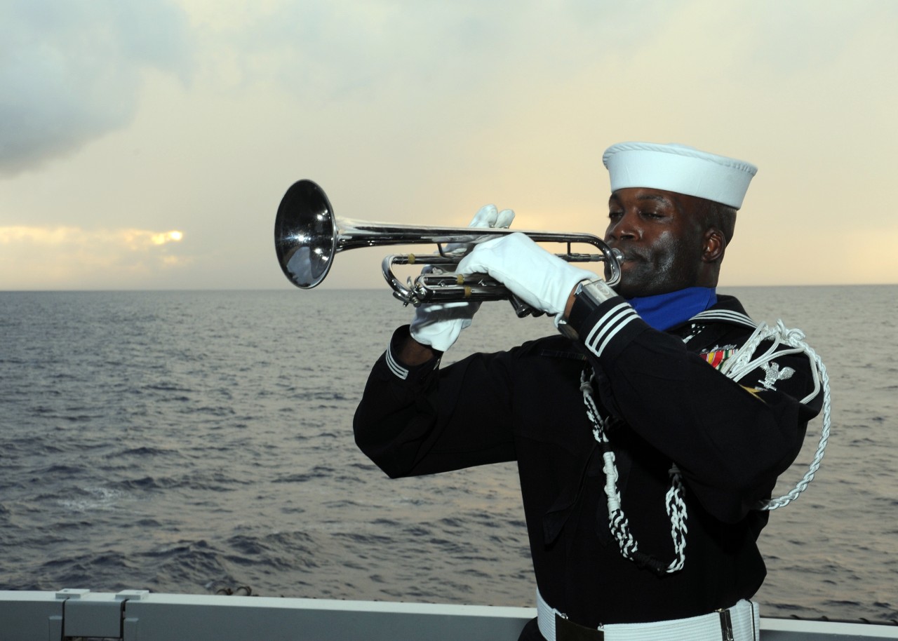 110710-N-ZZ999-056:  USS Enterprise (CVN-65), 2011. Boatswain’s Mate 1st Class Timothy Lumpkin plays the trumpet during a burial at sea ceremony aboard the aircraft carrier USS Enterprise (CVN-65). Enterprise and Carrier Air Wing (CVW) 1 are completing a deployment to the U.S. 5th and 6th Fleet areas of responsibility. Photograph by Mass Communication Specialist Seaman Gregory A. Pickett II, July 10, 2011.  Official U.S. Navy Photograph.  