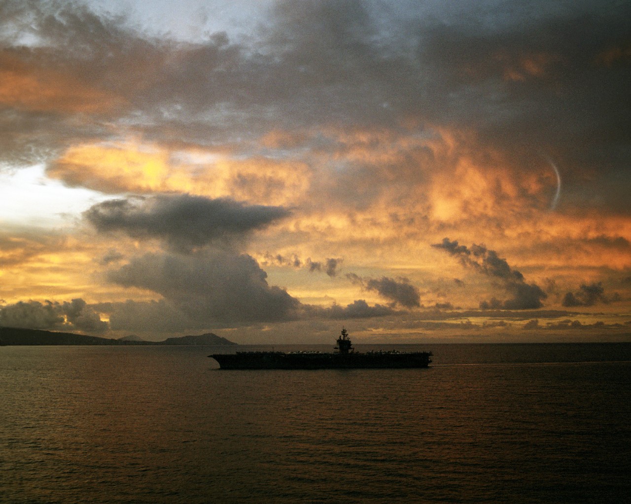 330-CFD-DN-SC-85-07419:  USS Enterprise (CVN-65), 1984.   Silhouetted port beam view of the aircraft carrier as she enters Pearl Harbor, Hawaii, July 15, 1984.   Official U.S. Navy Photograph, now in the collections of the National Archives.  (2017/11/30).  