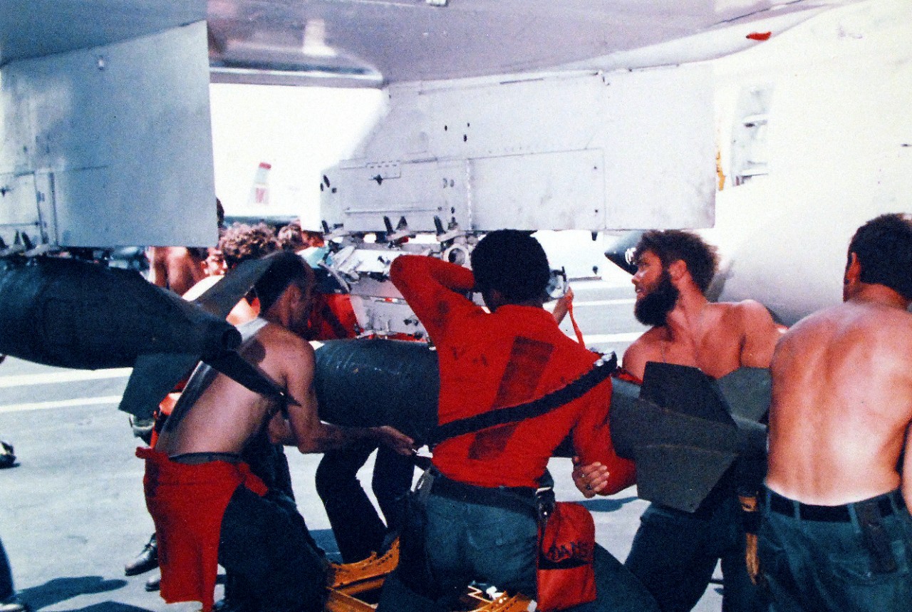 428-GX-K-107383:  USS Enterprise (CVN-65), 1975.  Ordnance personnel of Attack Squadron 97 (VA-97), strain to attach a 1,000 pound bomb to a squadron A-7E “Corsair II” attack aircraft on board USS Enterprise (CVAN-65) while in the Pacific Ocean. Photographed by PH3 Harold Brown, March 17, 1975.   U.S. Navy photograph, now in the collections of the National Archives. Official U.S. Navy Photograph, now in the collection of the National Archives.  (2015/12/15).