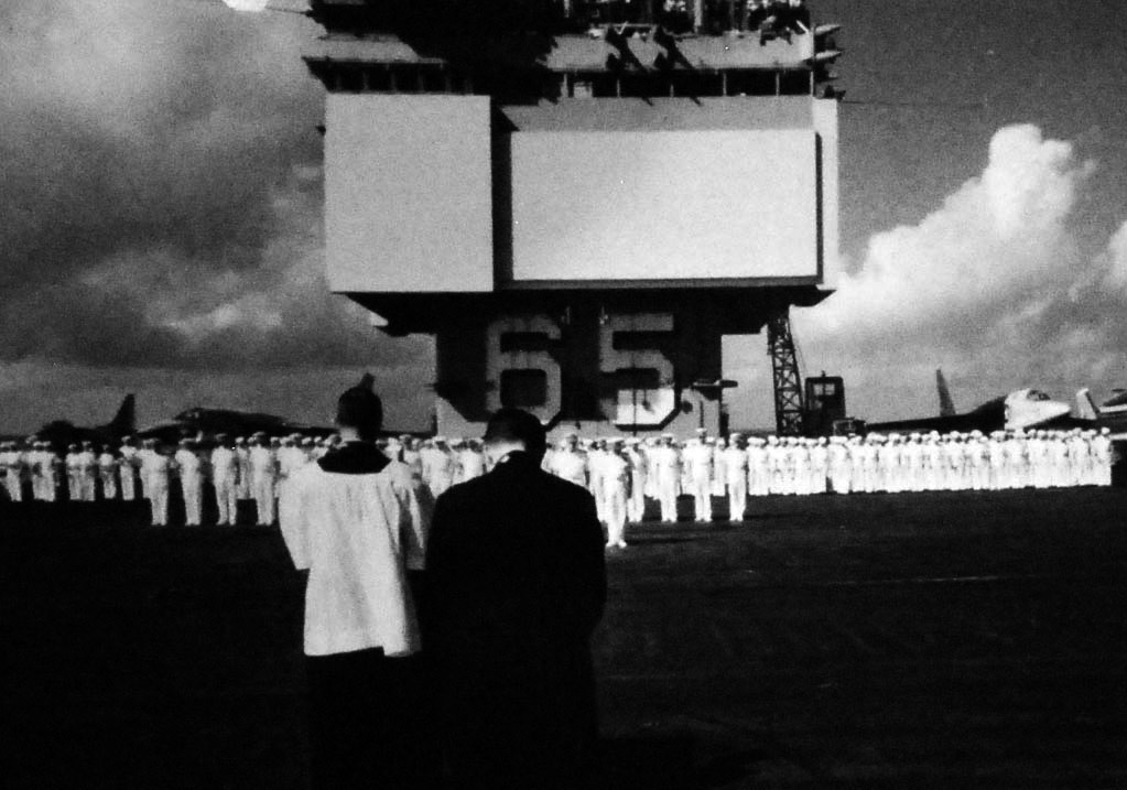 428-GX-K-31462: USS Enterprise (CVAN-65), 1966.  Navy heads are bowed in prayer on board USS Enterprise (CVAN-65) during memorial services for airman lost in combat over Vietnam. The services include presentations of the colors, the National Anthem, reading of scriptures, the Navy Hymn, a 21-round volley by the ship’s saluting battery, and taps.  Both Catholic and Protestant chaplains officiate the war’s most solemn occasion.  Photographed by PH1 W. M. Powers, 14 April 1966. Official U.S. Navy Photograph, now in the collection of the National Archives.   (2014/5/1).  Original negative is color.   