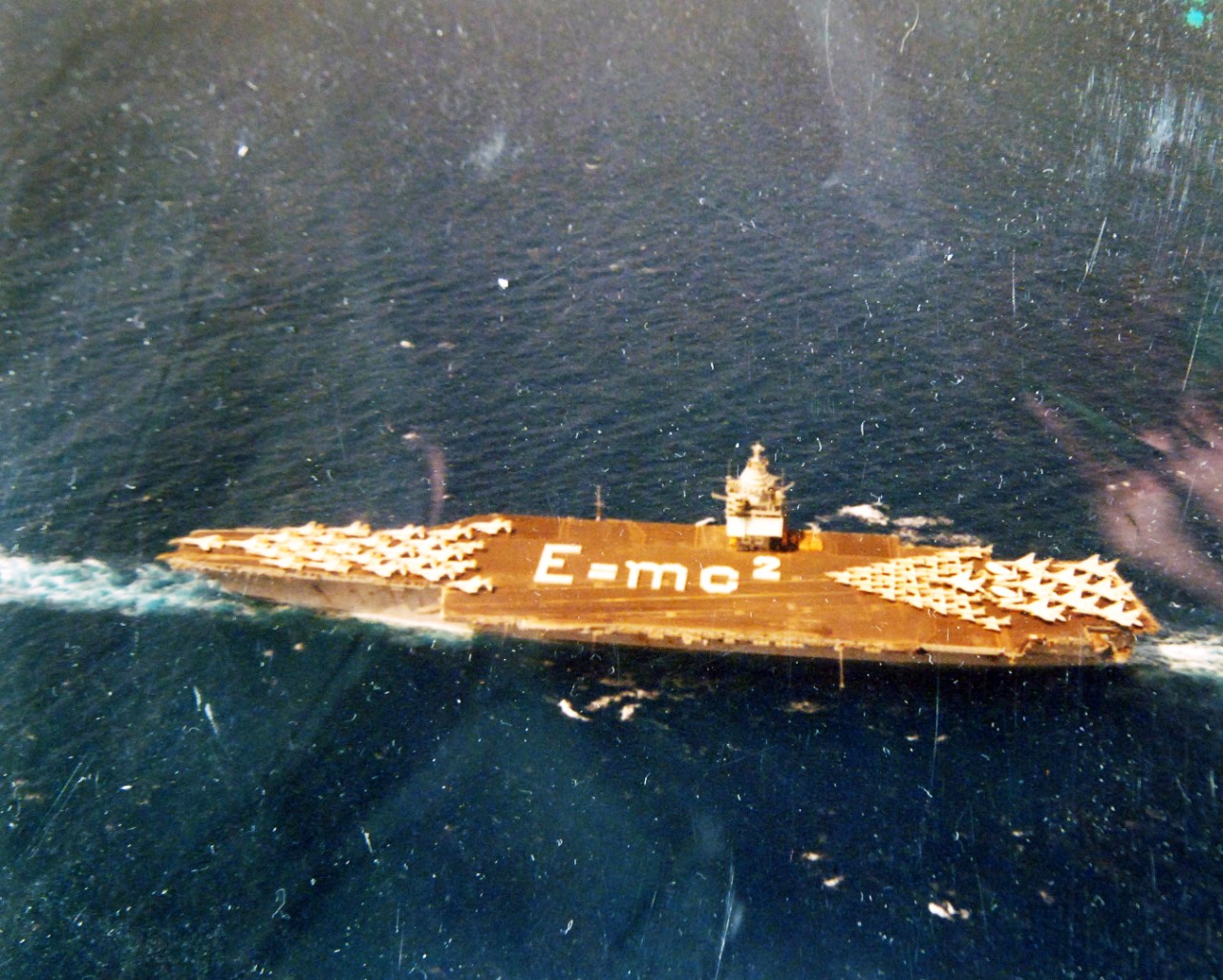 428-GX-KN-11207:  USS Enterprise (CVAN-65), 1964.   Operation Sea Orbit, the first surface around the world cruise, without replenishment, of Nuclear Task Force One, comprising of USS Enterprise, USS Long Beach (CGN-9), and USS Bainbridge (DLGN-25). Crewmembers onboard CVAN-65 form the equation for Einstein’s Theory of Relativity.    Photographed by Lieutenant R.R. Conger, July 21, 1964.    Official U.S. Navy Photograph, now in the collections of the National Archives.  (2017/11/29).  