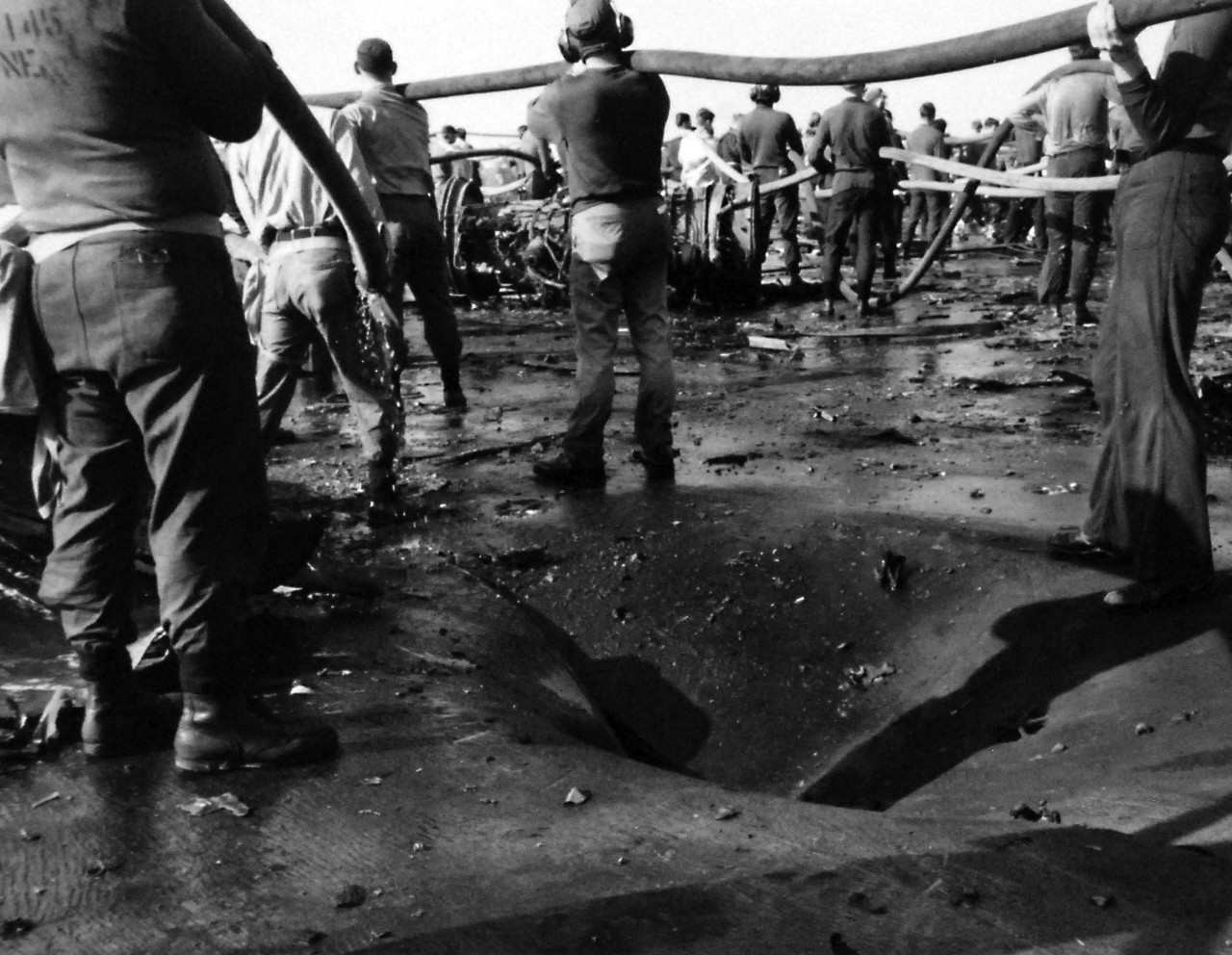 428-GX-USN-1140815:     USS Enterprise (CVAN-65), January 1969.     Pacific Ocean.  Crewmen of USS Enterprise (CVN 65) man hoses to fight a fire on the fight deck.  A bomb hole, in the foreground, is part of the damage which was caused during the fire which broke out as the ship was conducting air operations 75 miles south of Pearl Harbor.  Photographed by PH1 W.R. Dappen, January 14, 1969.       Official U.S. Navy photograph, now in the collections of the National Archives.   (2016/07/26).