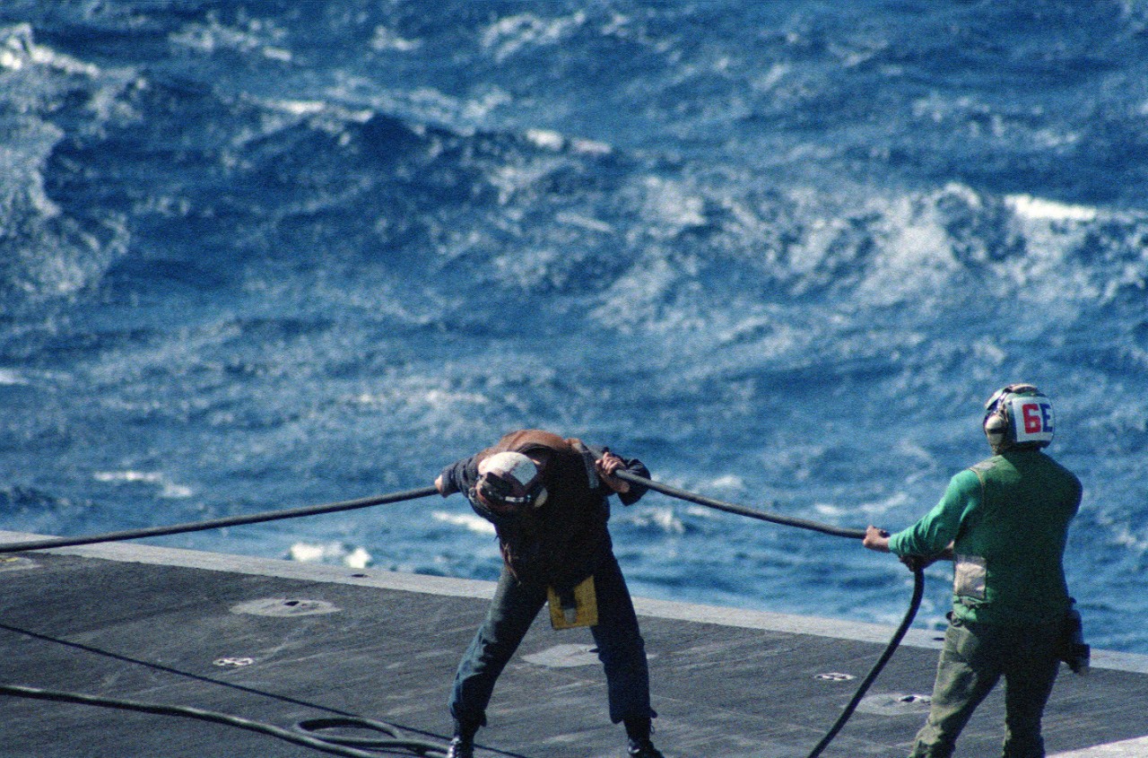 330-CFD-DN-SC-89-02671:  USS Forrestal (CV-59), 1988.   Flight deck crewmen pull a cable across the flight deck of the aircraft carrier USS Forrestal (CV-59) during Exercise WEST WIND 88, September 1, 1988.  PH3 Farrington, USN.  Official U.S. Navy Photograph, now in the collections of the National Archives.    