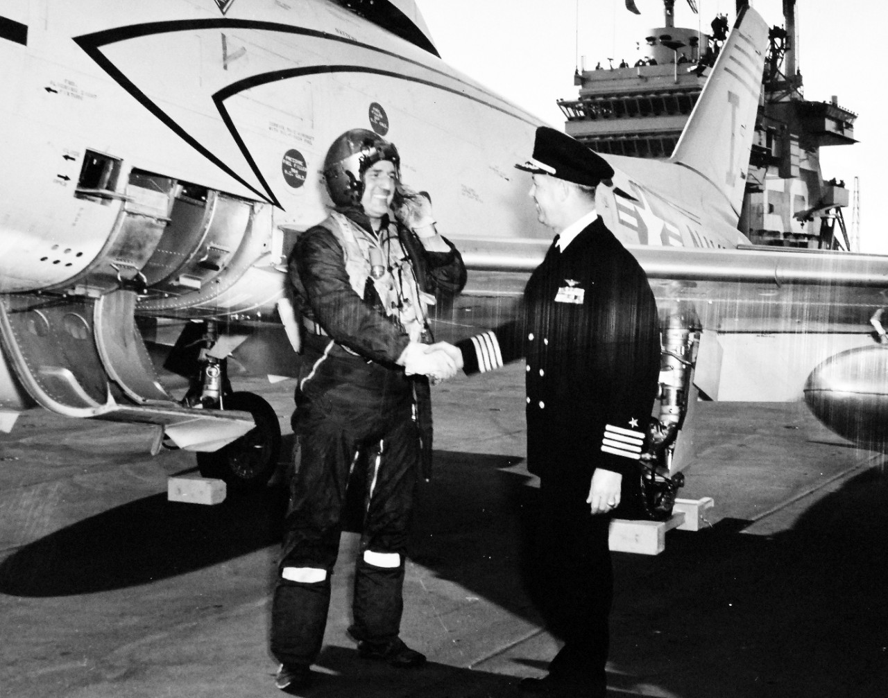 330-PS-7642 (USN 684245):  USS Forrestal (CVA-59), 1956.    Captain Roy Lee Johnson, USN, Commanding Officer of USS Forrestal (CVA-59), congratulates Commander Ralph L. Werner, USN, after making the  first landing onboard the giant carrier.   Werner piloted the U.S. Navy FJ-3 “Fury” jet aircraft in the background.  Werner commanded Air Task Group 181 (ATG-181) and landed approximately 2:40 (EST), January 3, 1956 while the aircraft carrier, operating at sea east of Norfolk, Virginia, was undergoing a series of routine tests.  Commander Werner made three touch-and-go landings before making the first full-stop landing.  A few hours later, piloting the same aircraft, he also made the first catapult launch from the carrier.   Aircraft used for these trials are based at the U.S. Naval Air Station, Oceana, Virginia.  Later, at approximately, 2:45 (EST), Commander W.M. Harnish, USN, Commanding Officer, Squadron 21 (a unit of ATG-181), piloting a U.S. Navy FJ-3 “Fury” made the second landing on board Forrestal.    Commander Harnish’s father, Mr. W.E. Harnish, was the Professor of Education at the University of Illinois.  Lieutenant Vincent Darcey, USN, of ATG-181, was the Landing Signal Officer for both landings.  Both aircraft were painted with the new white and grey “atomic” paint scheme.    Photograph released January 4, 1956.   Offical U.S. Navy Photograph, now in the collections of the National Archives.  (2015/02/18)  