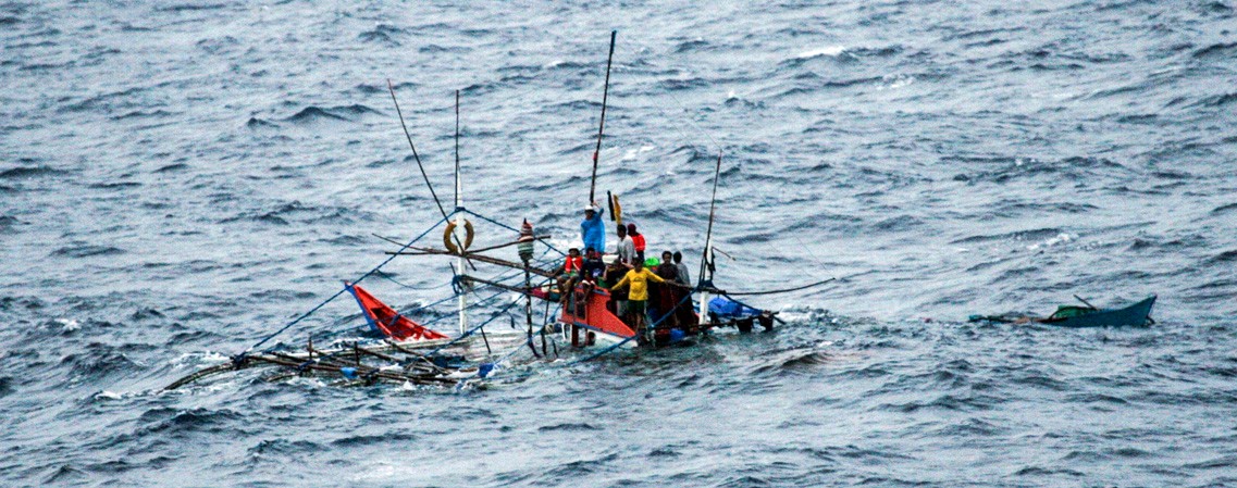 Distressed fishermen await their rescue from their sinking fishing ship by the Impeccable-class ocean surveillance ship.