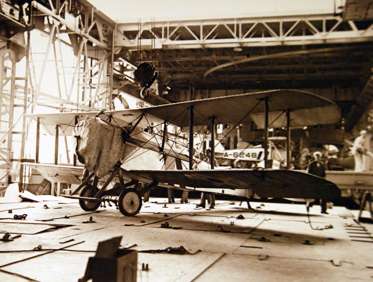 19-NS-L11:  USS Langley (CV 1), 1923.  Vought AS-1 or VE-7 Plane on deck, 19 July 1923.   Air plane slung on traveling crane.  Note size of hook on crane.    Official U.S. Navy photograph, now in the collections of the National Archives.   (2014/07/2) 