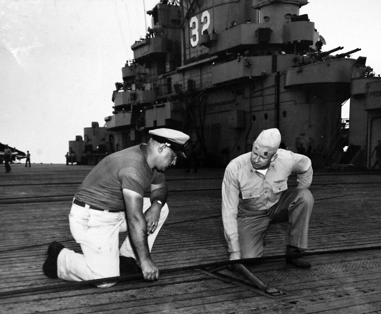 80-G-405968: USS Leyte (CV-32), June 1949.   Reserve Cruise Onboard.  Left to right:  ABC E.C. Endres, USN, and LT C.L. Schulten, USNR, inspecting the cross deck pendants on the flight deck.   Official U.S. Navy photograph, now in the collections of the National Archives.  (2017/02/07).