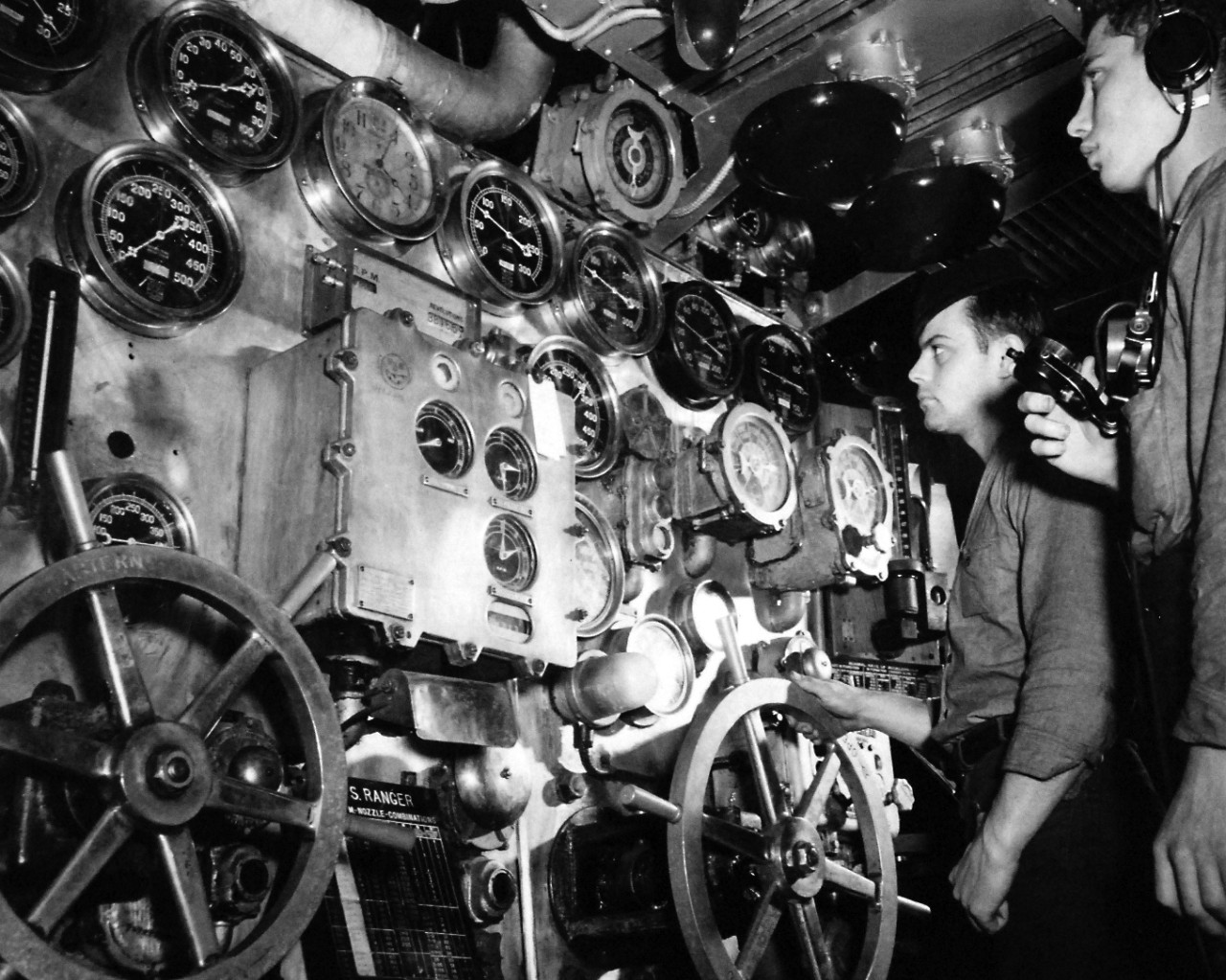 80-G-36675:   USS Ranger (CV 4), 1943.    Engine Room.   Main Throttle Board in forward engine room.  Machinist’s Mate standing the throttleman watch must keep engines at proper speeds.  The phone talker is in constant communication with the bridge and main control.   Photographed January 1943.   Official  U.S. Navy Photograph, now in the collections of the National Archives.  (2016/11/25).  
