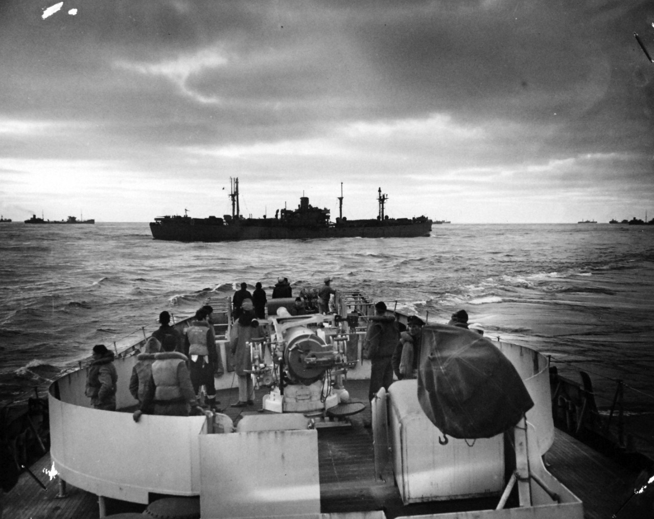 26-G-1523:  Sinking of German submarine U-175, April 1943.   The submarine was sunk off south-west of Ireland by USCGC Spencer (WPG-36) on April 17, 1943.     Official Caption: ""COAST GUARD CUTTER SINKS SUB: Target of the Nazi U-Boat -- These ships in the convoy being shielded by the U.S. Coast Guard Cutter USCGC SPENCER (WPG-36) steam past the warship just before the latter detects the underseas [sic] raider and swings into action.  The U-Boat, endeavoring to break into the center of the convoy, was sunk." Date: 17 April 1943 (Note on the back of the photo notes: "Not to be released for publication or announced to the public before 10:00 A.M. Eastern War-Time, June 2nd.") Official U.S. Coast Guard Photograph, now in the collections of the National Archives.  (2017/09/05).
