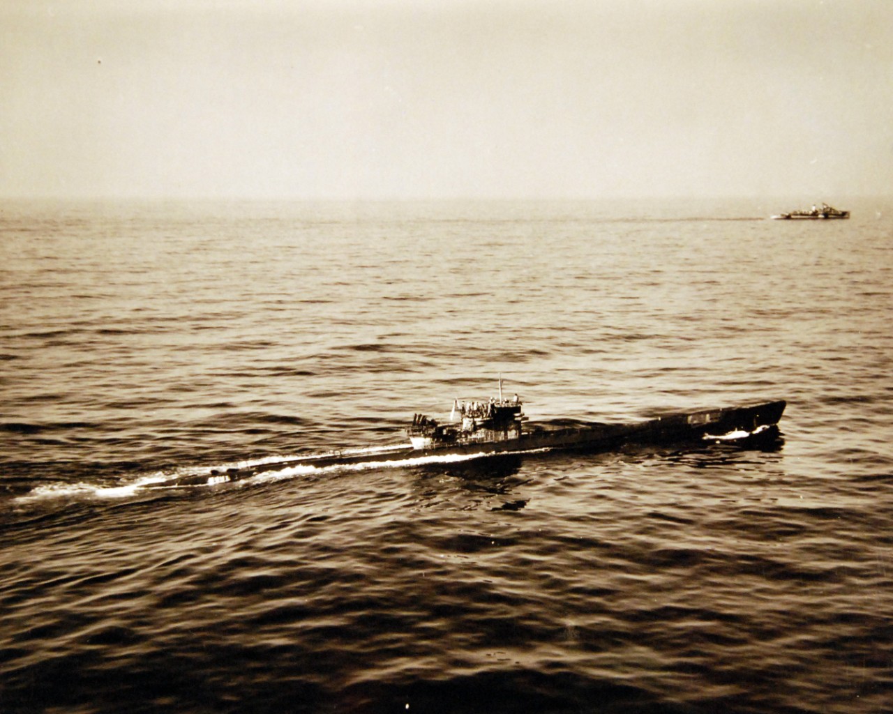80-G-320305: Surrender of German U-boats, WWII.  Surrender of German U-boat, U-858, 700 miles off the New England Coast to two destroyer escorts, May 10, 1945.  Shown:  U-858 arrives at the point of rendezvous flying U.S. colors.  In the background is one of the Des which escorted the submarine.  Official U.S. Navy Photograph, now in the collections of the National Archives.  (2017/07/18).