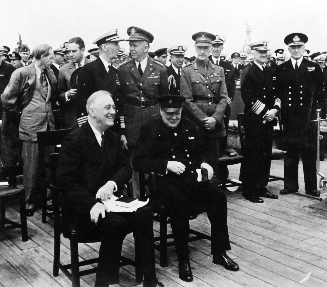 80-G-26854: Atlantic Charter, August 1941.  President Franklin D. Roosevelt and Prime Minister Winston S. Churchill and high-ranking naval and military men of both nations following divine services onboard Royal Navy battleship HMS Prince of Wales during the Atlantic Charter.  Standing left to right:  Harry Hopkins; Averill H. Harriman; Admiral Ernest J. King; General George C. Marshall; Rear Admiral Ross T. McIntire; General Sir John Dill; Captain John R. Beardall; Admiral Harold R. Stark; Admiral Sir Dudley Pound.  Photograph released August 10, 1941.  Official U.S. Navy Photograph, now in the collections of the National Archives.  (2016/03/22).