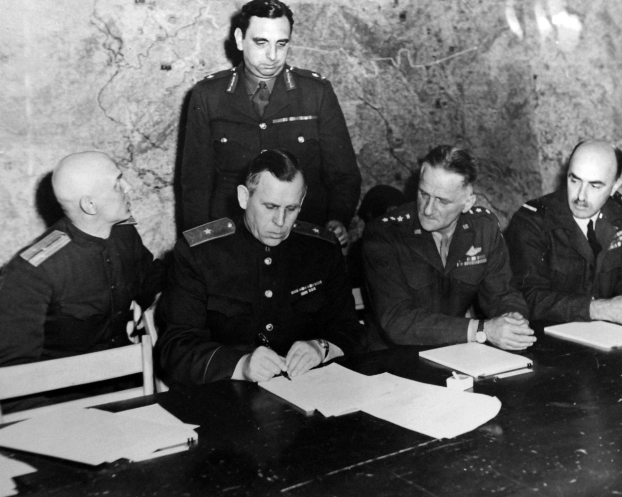 SC-111-SC-27463:   Surrender of Germany, May 7, 1945.  Major General Ivan Alexeyevich Susloparov, Russian Delegate to the SHAEF French Mission and representing the Soviet government, signs the Document of German Capitulation in the War Room of Supreme Headquarters, Allied Expeditionary Forces, at Reims, France, at his left is General Carl A. Spaatz, CG, US Staff, and Air Marshall Sir J.M. Robb, on General Susloparov’s right is Lieutenant Ivan Cherniaeff, Russian Interpreter.  Standing is Major General K.W.D. Strong, G-2, SHAEF.  U.S. Army photograph.  Courtesy of the Library of Congress Collection, Lot-8988. (2015/10/16).