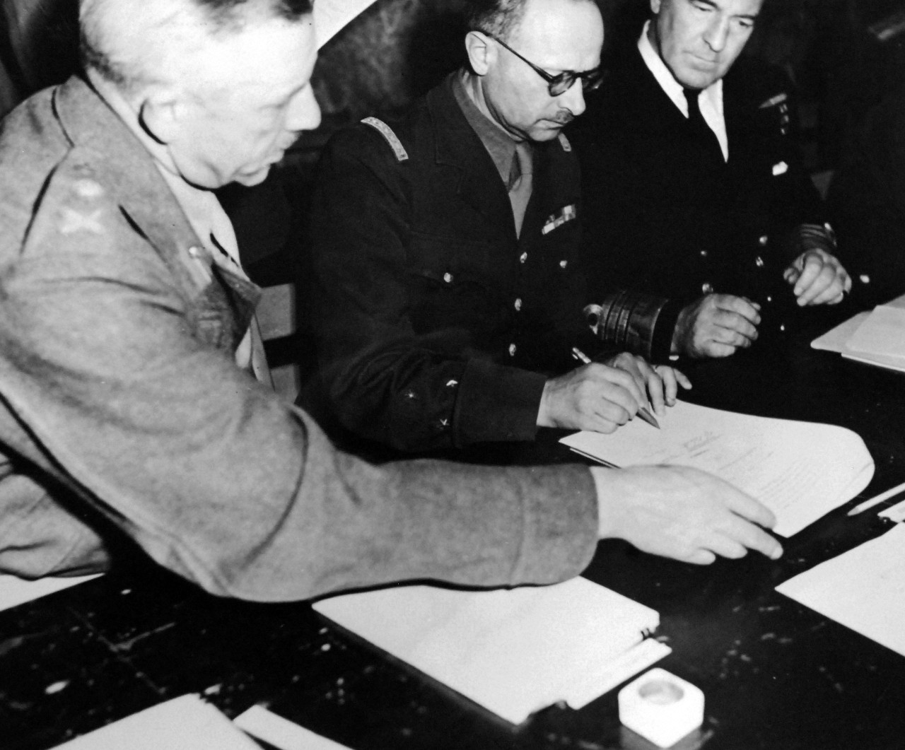 111-SC-27464:   Surrender of Germany, May 7, 1945.  General Francois Sevez, Representative of General Alphonse Juin, Chief of Staff to General de Gaulle, is here shown affixing his signature to the document under which all remaining German resistance capitulated, on his right is Lieutenant General Sir F.E. Morgan, Deputy Chief of Staff, and on his left is Admiral Harold M. Burrough, Commander in Chief, Allied Naval Expeditionary Forces.  U.S. Army photograph.  