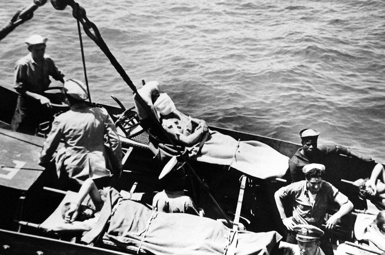 26-G-1977:   Operation Avalanche, September 1943.  Mercy Accompanies Invasions.  Coast Guardsmen in the landing craft carefully prepare the wounded, lashed to their stretchers, for hoisting aboard the Coast Guard manned transport.   A chair from some Italian building has been utilized to prop one man up in his stretcher, a position dictated by the nature of his injuries.  Every effort is made to give proper care to the wounded.  Note the African-American sailor to the left.   Official U.S. Coast Guard Photograph. Photographed through Mylar sleeve.   Courtesy of the Library of Congress.  (2016/05/19). 