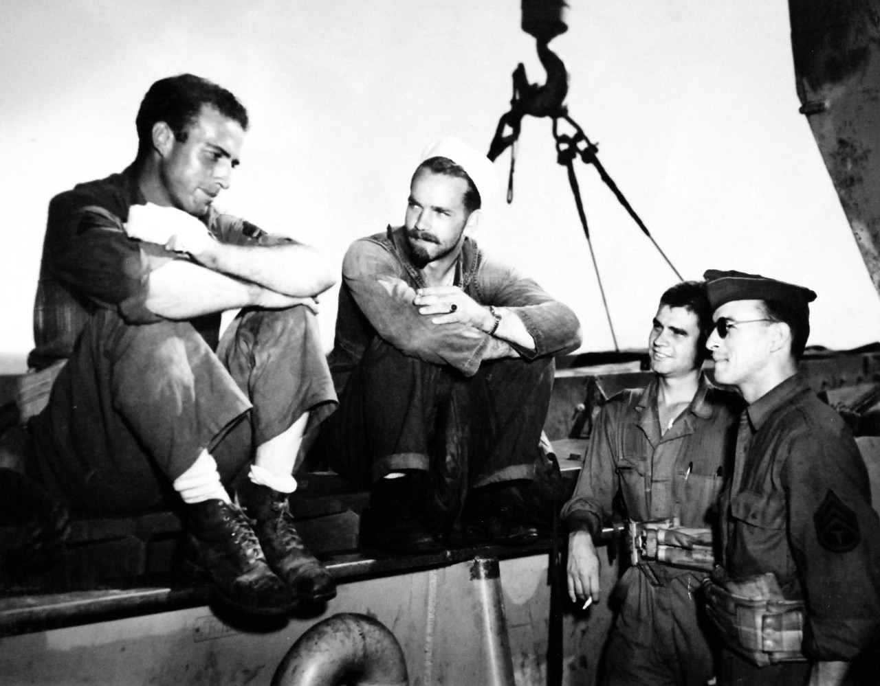 26-G-1989:  Operation Avalanche,  September 1943.   Comparing Close Calls.  Comparing close calls with death was a favorite conversational subject among soldiers and Coast Guardsmen onboard a Coast Guard manned transport returning from Salerno.  Shown from left to right:  Sergeant Curtis F. Ellison; Coast Guardsman C.B. Lewis; Private First Class Harold Norman; and Sergeant Edmond Gosselin.   Official U.S. Coast Guard Photograph, now in the collections of the National Archives.   (2015/5/19). 