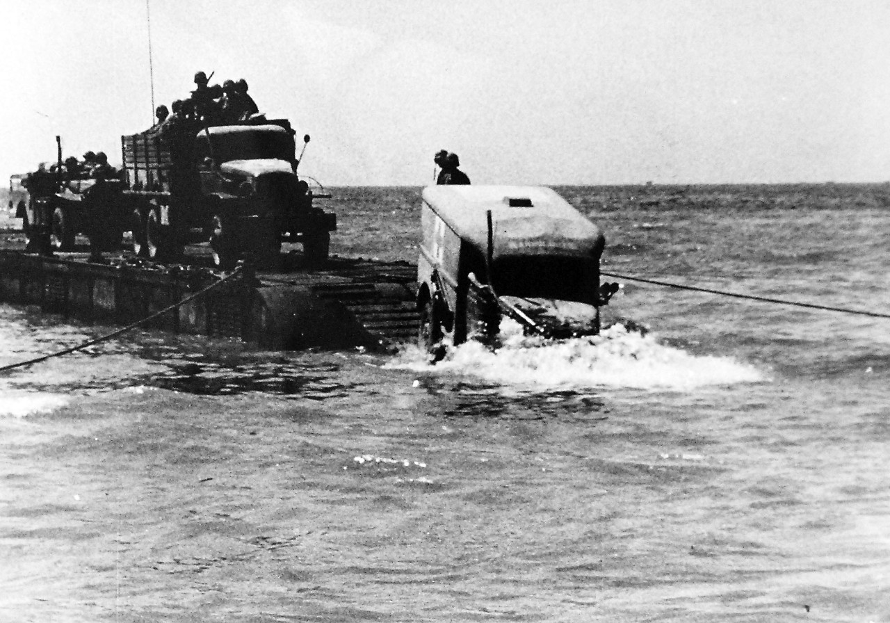 26-G-92443-6:   Operation Avalanche, September 1943.  End of the Bridge -- Nose Dive.   Down a ramp, leading from an assault landing ship, this Medical Corps truck was taking a nose dive into the surf as a Coast Guard truck was taking a nose dive into the surf as a Coast Guard combat photographer took the picture.  Coast Guardsmen piloted the landing craft onto enemy beaches, and then supplies rolled out in a volume that sent the Axis reeling back into Italian mountains.  Official Coast Guard Photograph. Photographed through Mylar sleeve.   Courtesy of the Library of Congress.  (2016/05/19). 