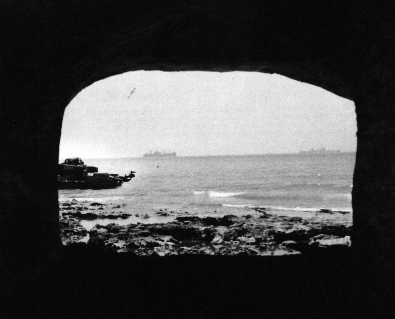 80-G-42512:   Operation Husky, July-August 1943.    Scoglitti, Sicily, after successful landing operations in the invasion of Sicily.  View of harbor from interior of pill box, looking south.  At left, a tanker lighter patrols the shore.   Photographed on July 11,  1943. Official U.S. Navy photograph, now in the collections of the National Archives.    (2014/8/13). 
