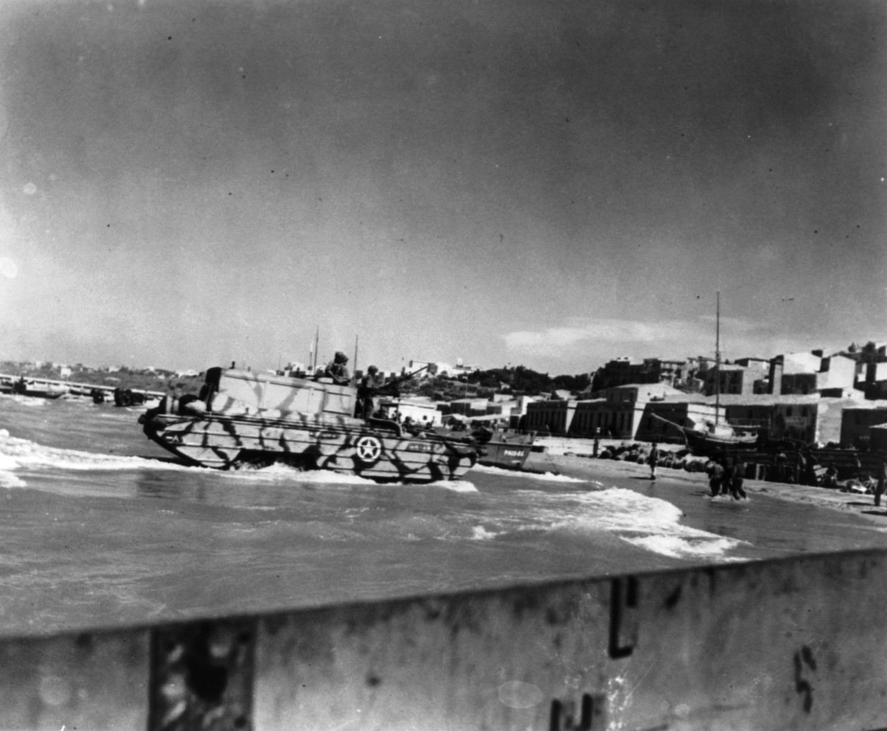 LC-USZ62-80656:  Invasion of Sicily, Italy, July 9 – August 17, 1943.   U.S. Army amphibious, DUKWs, roll ashore in Sicily as a Coast Guard-manned transport disgorges men and material for the invasion.  Coast Guardsmen and soldiers already on shore can be seen at right, July 1943.  (7/17/2015). 