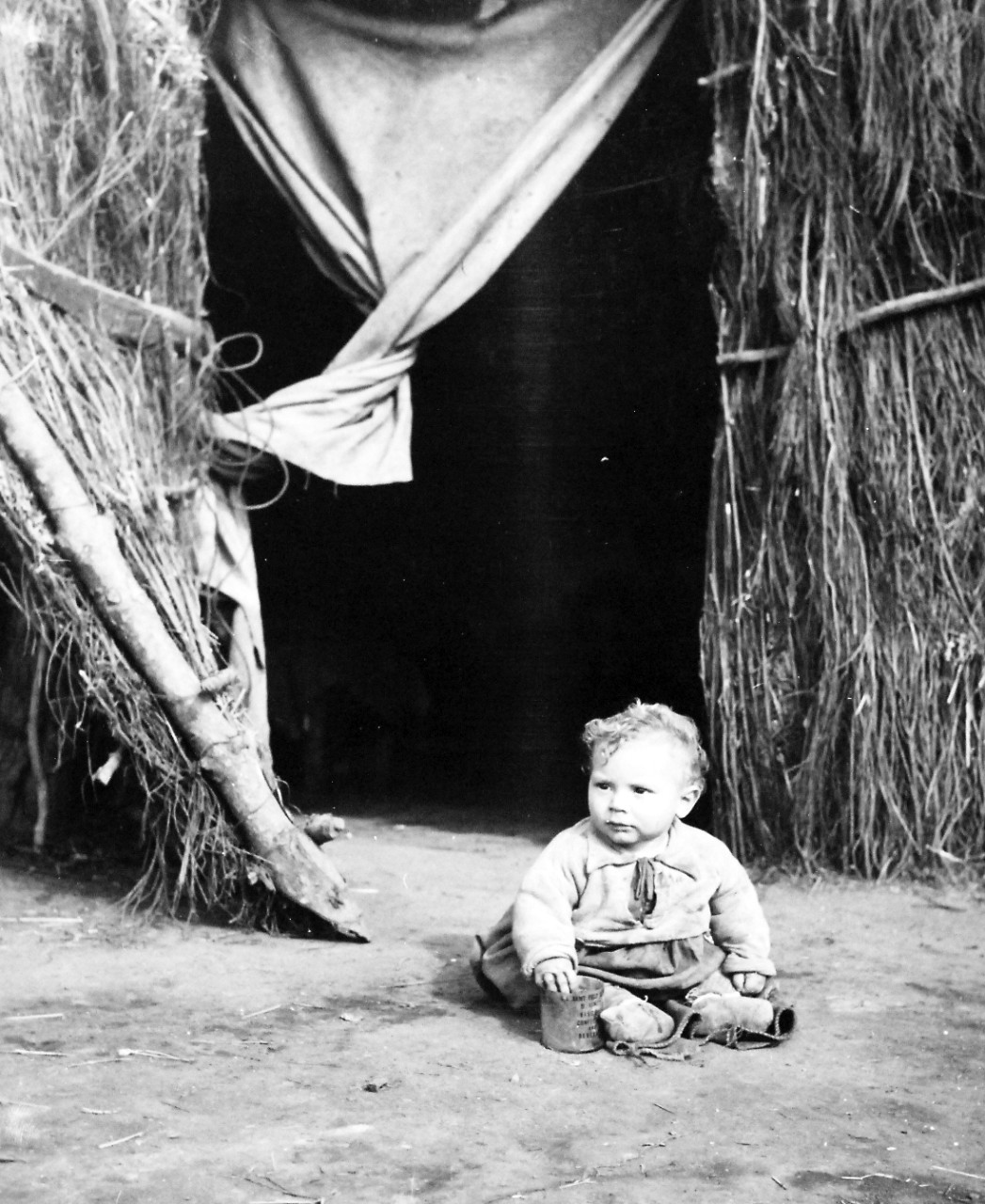 80-G-58429:    Battle of Anzio, January-June 1944.     Italians of Anzio, Italy.  Italian boy-baby poses for his picture outside his grass home.      Official  U.S. Navy photograph, now in the collections of the National Archives.  (2016/06/28).