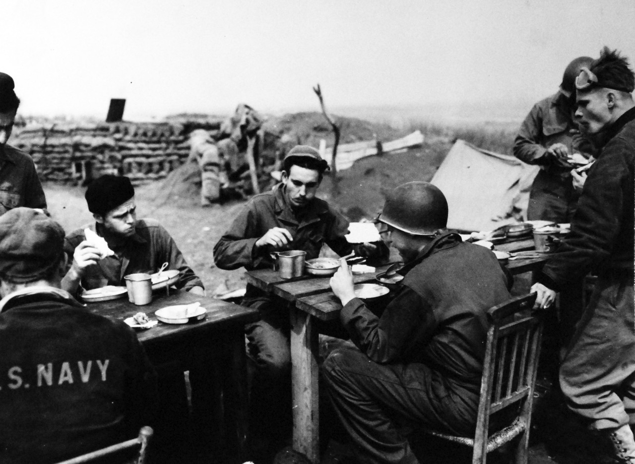 80-G-59379:    Battle of Anzio, January-June 1944.    US Navy Salvage Detachment at Anzio, Italy.   These US Navy sailors gulp their chow at an outdoor mess on the front below Rome.  Photograph released on 25 April 1944.    Official U.S. Navy Photograph, now in he collections of the National Archives.  (2014/03/12).    