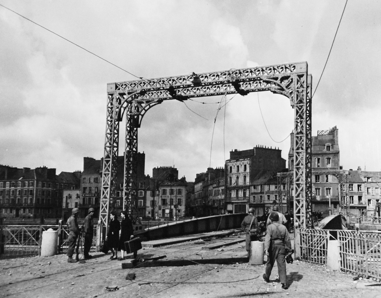 80-G-255915:    Normandy Invasion, Cherbourg, France, July 1944.   French civilians pass over damaged bridge to return to their homes in Cherbourg, France, after its liberation by Allies. The Army engineers move into the town at right.  Photograph received October 28, 1944.   Official U.S. Navy Photograph, now in the collections of the National Archives.   (2014/11/05). 