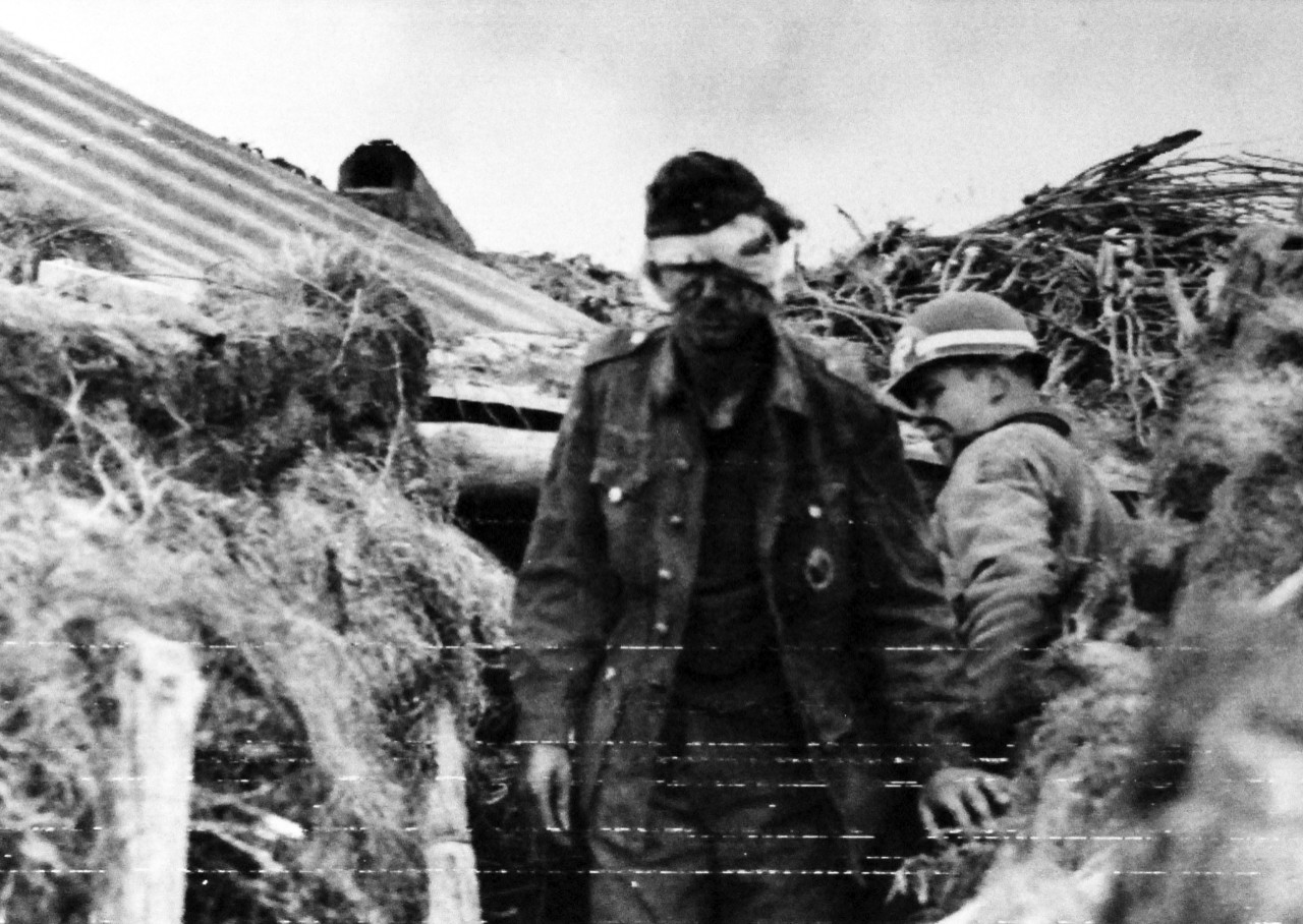 80-G-59416:   Normany Invasion, German Prisoners, June 1944.  Wounded German gunner is ushered out of a dugout by a watchful US Army MP following the surrender somewhere along the French coast, released 10 June 1944.   Official U.S. Navy Photograph, now in the collections of the National Archives.    (2014/3/12).   